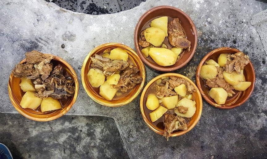 view from above of ceramic pots with ‘patatato’ Greek food means potatoes with meat in oven at The Authentic Big Blue